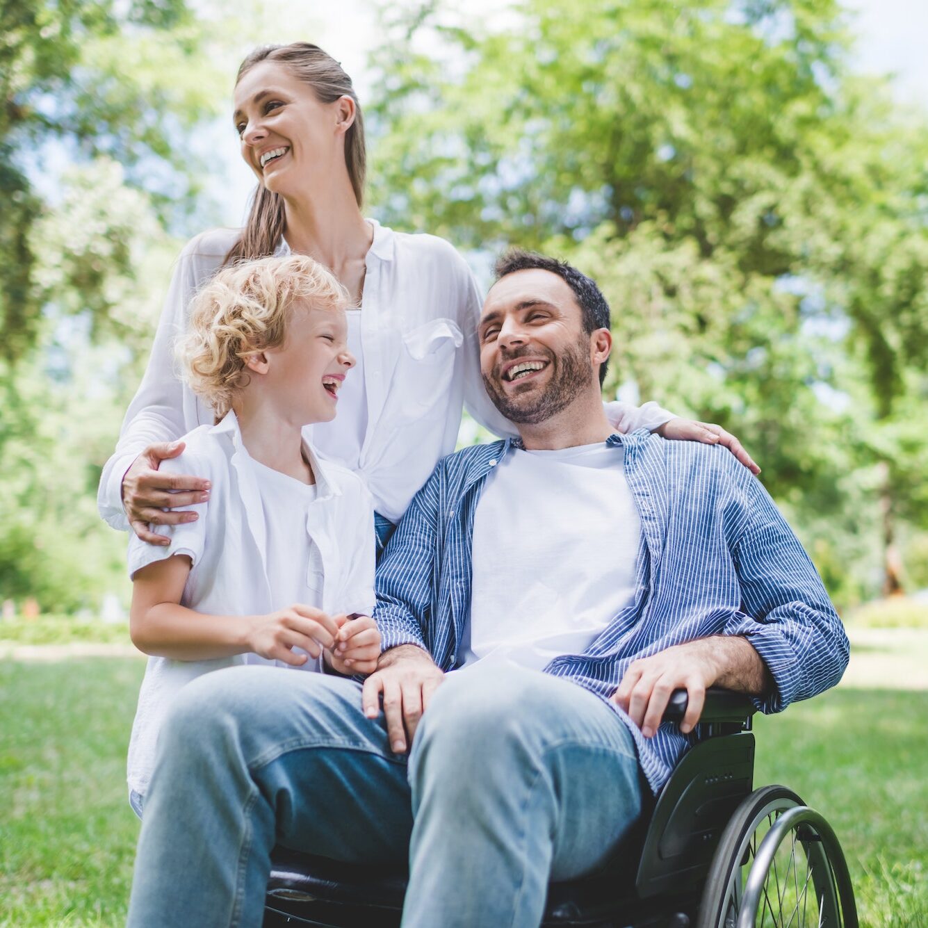 happy family with disabled father on wheelchair in park