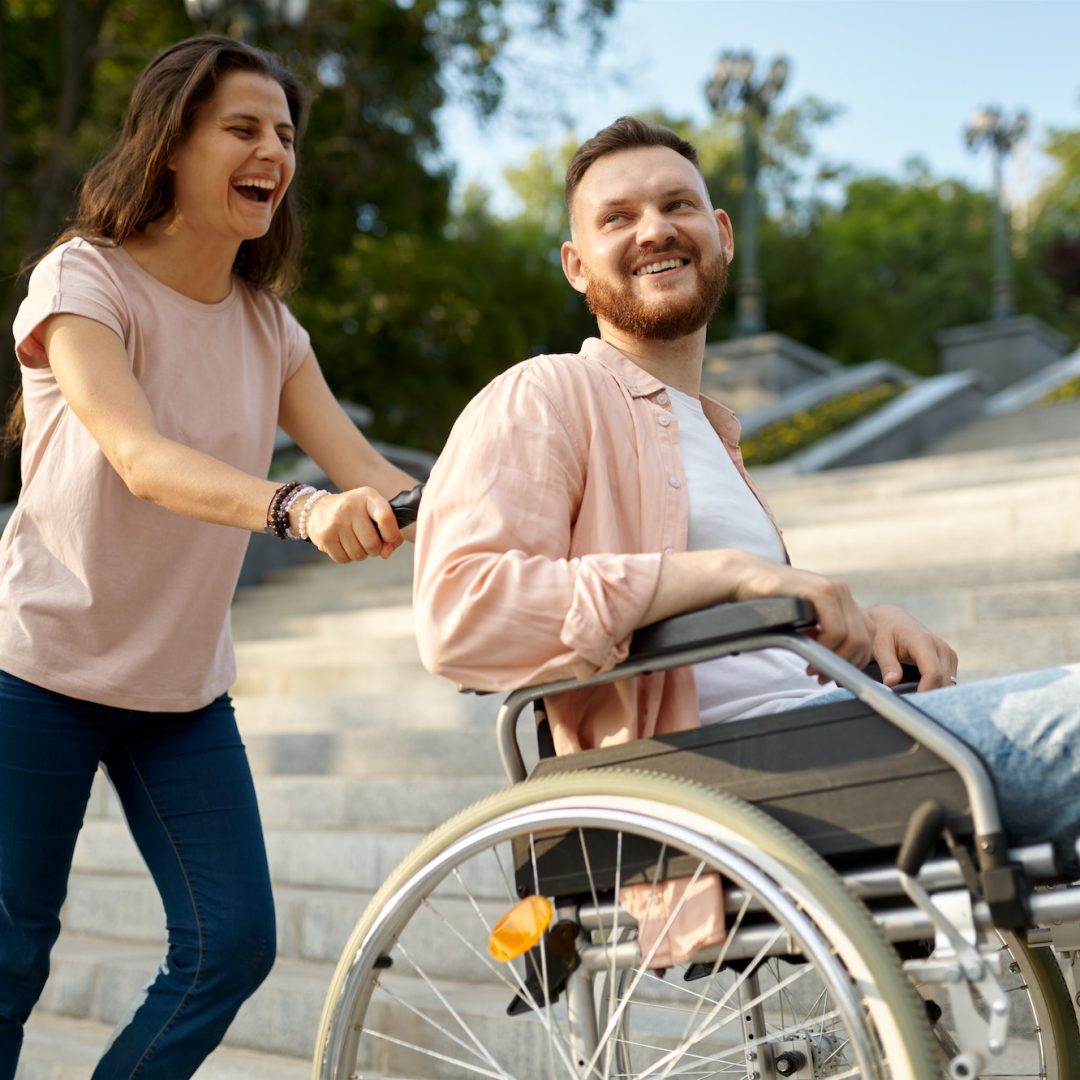 Couple with wheelchair goes up the stairs in park